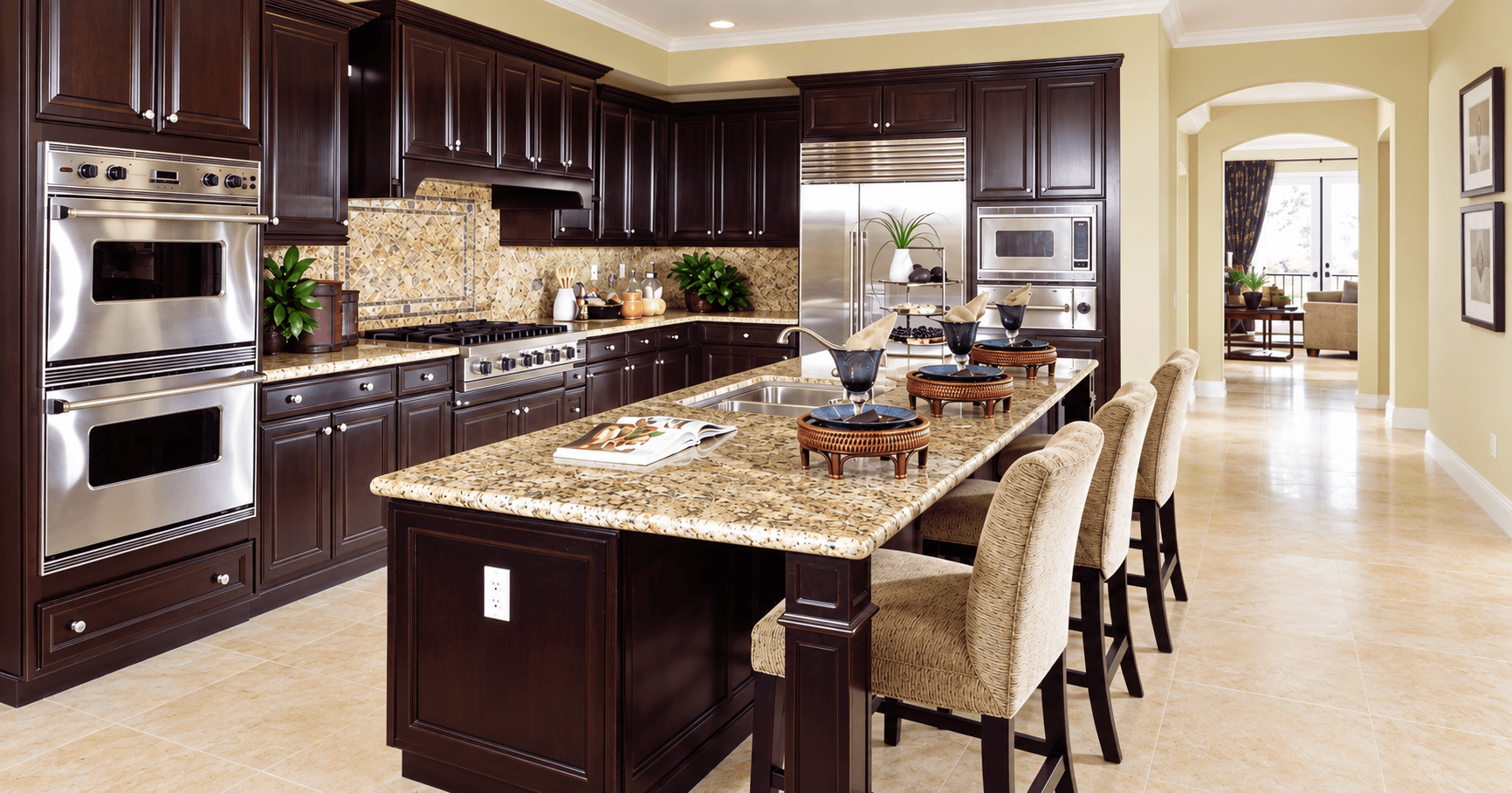 Dark wood kitchen with a large island topped in speckled tan and brown stone