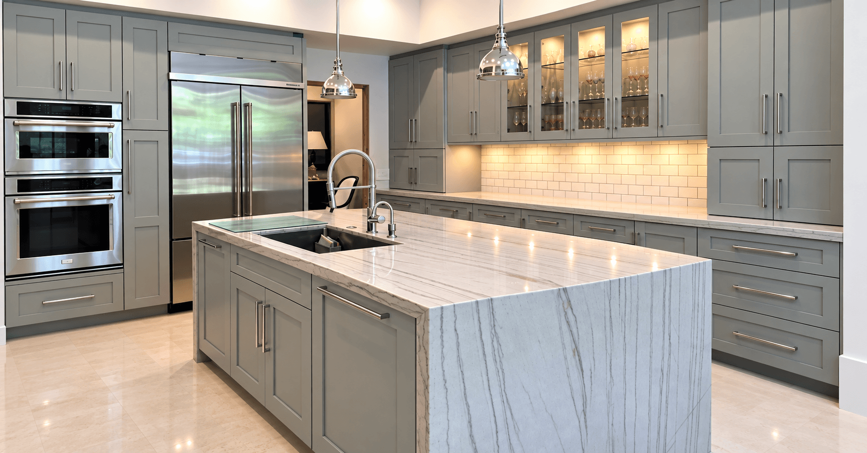 Gray-cabinet kitchen with a white stone waterfall island marked by long gray veining