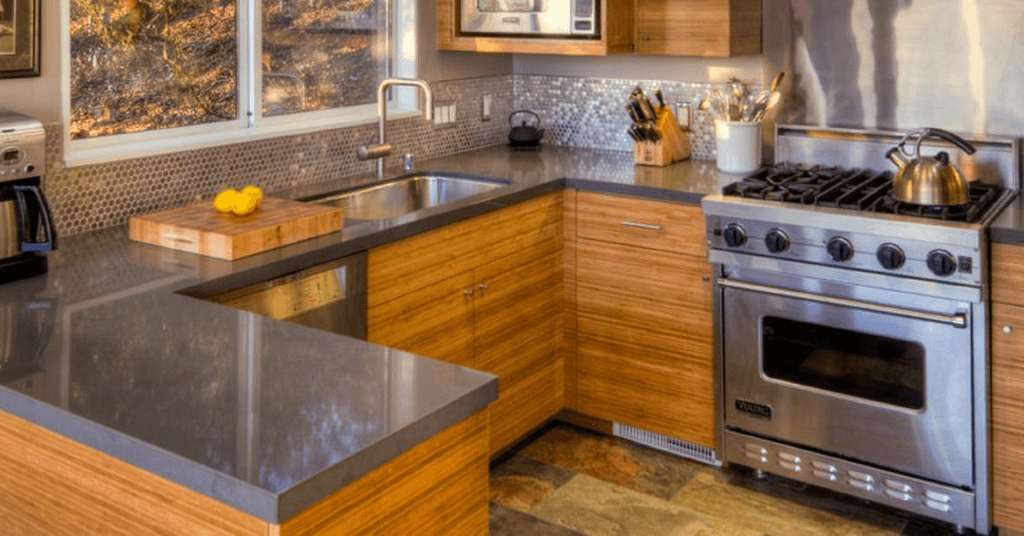 Warm wood kitchen with dark gray stone countertops wrapping the sink and range